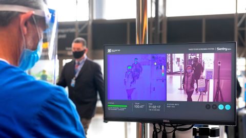 Passengers walks past thermal cameras, that check passenger's body temperatures, at Los Angeles International Airport in Los Angeles, California on June 23, 2020, after they were added as another layer of protection during the COVID-19 pandemic.