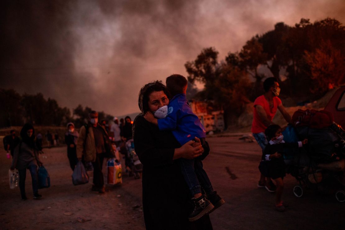 A woman carries a child after a fire broke out in the Moria migrants camp in Lesbos on September 9, 2020. 