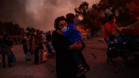 A woman carries a child after the fire tore through the migrant camp on the Greek Aegean island.