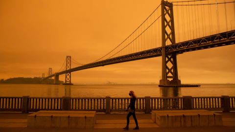 A woman walks under an orange smoke-filled sky in early September in San Francisco, California, as wildfires rage across the state.