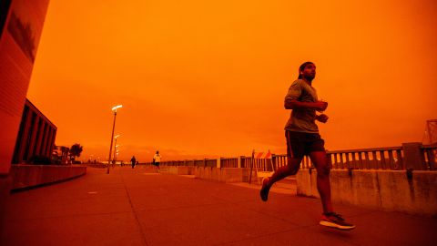 People jog along Embarcadero as smoky skies from the northern California wildfires casts a reddish color during the morning in San Francisco, Calif., on Wednesday, Sept. 9, 2020.