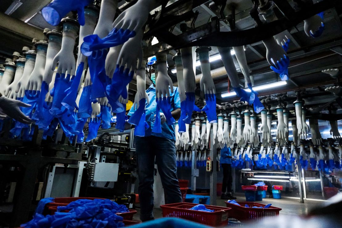 An employee monitors latex gloves on an automated production line at a Top Glove factory, February 18, 2020.