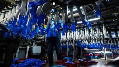 An employee monitors latex gloves on an automated production line at a Top Glove factory, February 18, 2020.