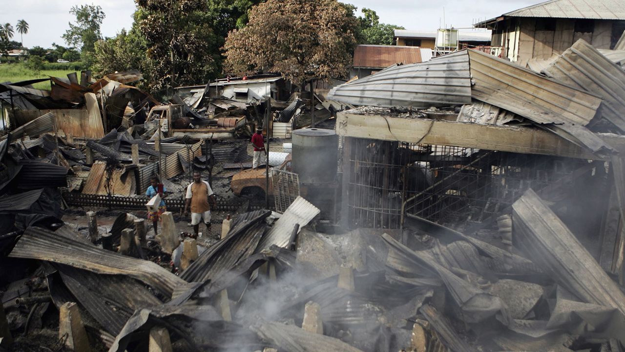 Locals search through the remains of smouldering buildings in Chinatown on April 21, 2006 following several days of rioting and looting in the Soloman Islands' capital, Honiara.