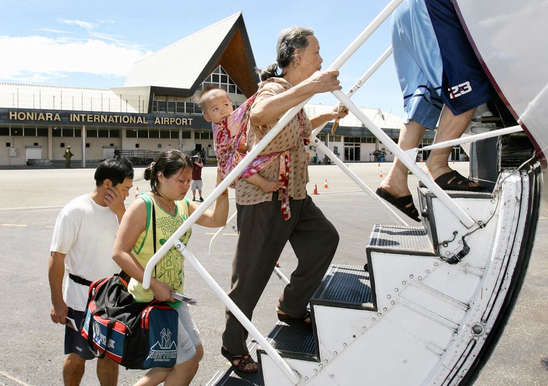 A mother and child board their flight as they are flown out of the  Solomon Islands on chartered aircraft provided by Beijing after losing all their possessions in the recent riots in Honiara, 23 April 2006.  