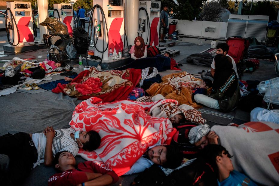 Migrants take refuge at a gas station.