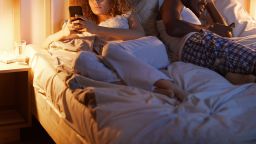 STOCK couple in bed using phones