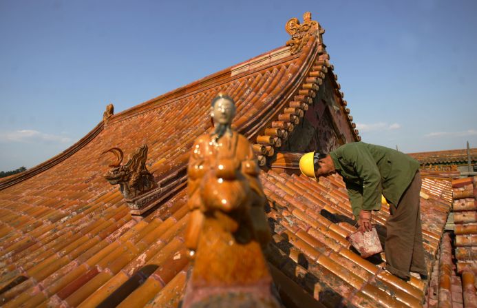 A worker repairs glazed tiles on the roof of Cining Palace, or Palace of Compassion and Tranquility, in the Forbidden City in April 2008, ahead of the Beijing Olympic Games.