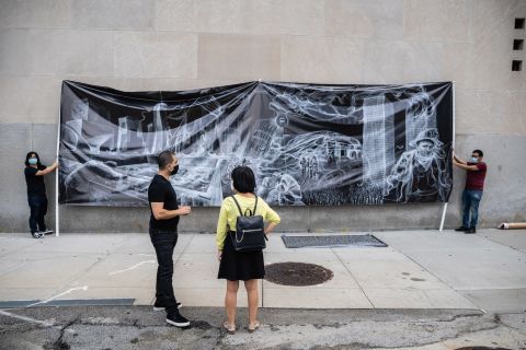 People stand in front of artwork commemorating 9/11.