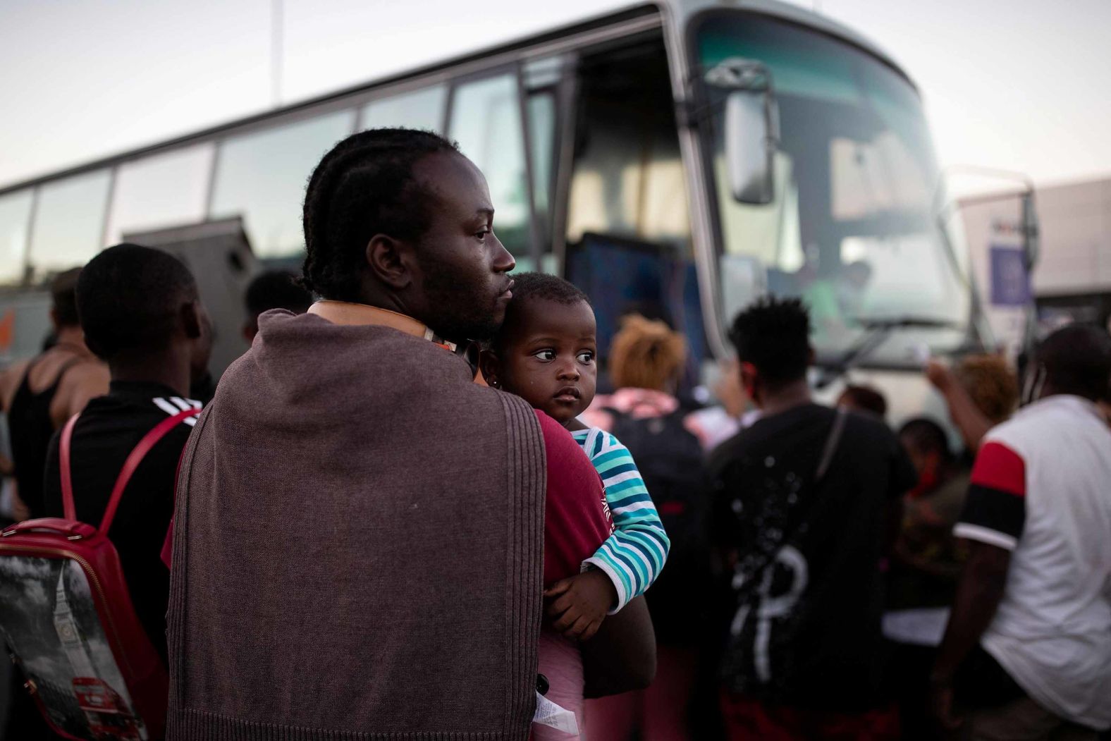 A man holds a baby as migrants wait to board a bus on Thursday, September 10.