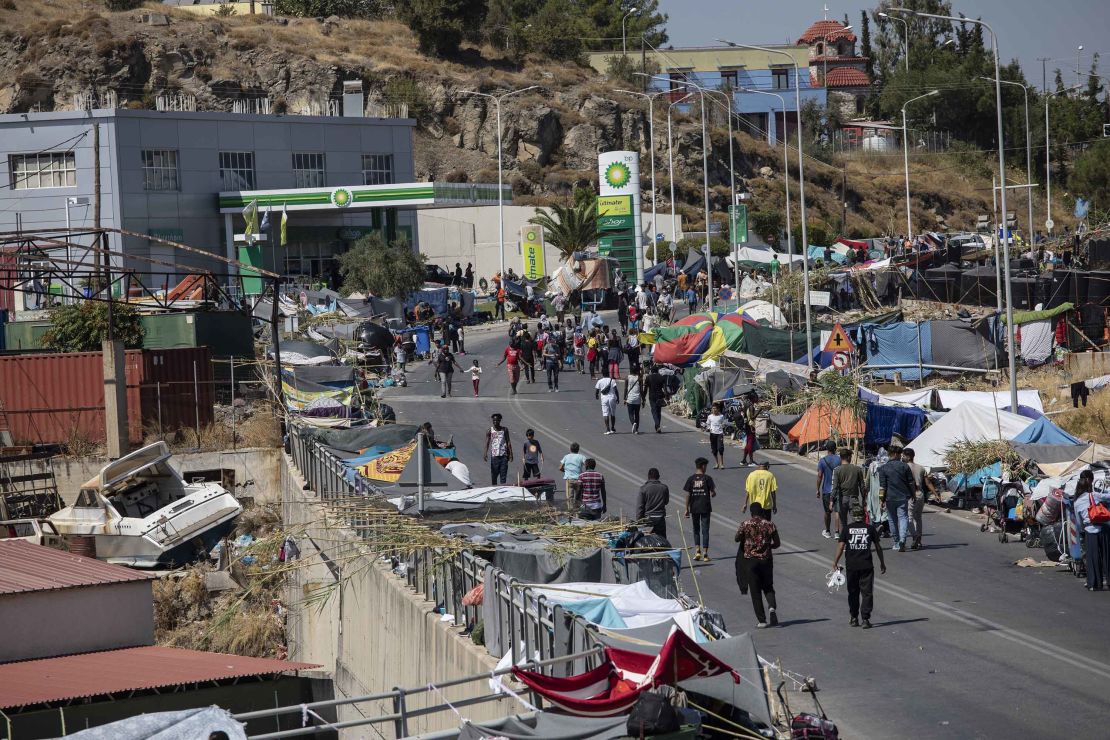 Homeless refugees and migrants gather on the road on Friday after thousands were left homeless following the devastating blaze.