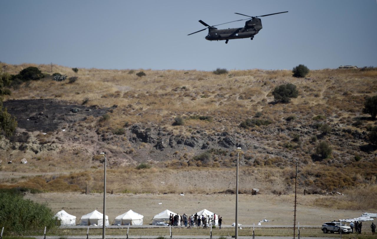 A Greek Air Force helicopter hovers over a military area near Panagiouda as officials prepare a tented area for people displaced by the fire.