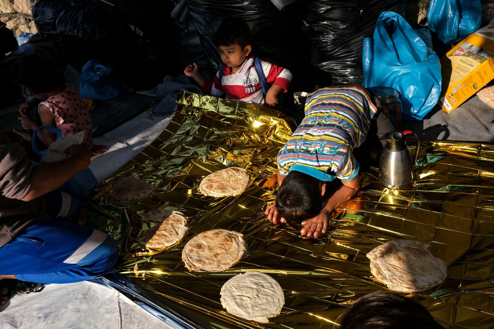 An Afghan boy expresses his thanks before eating breakfast, which included pita, honey and tahini spread, at his family's tent on September 11.