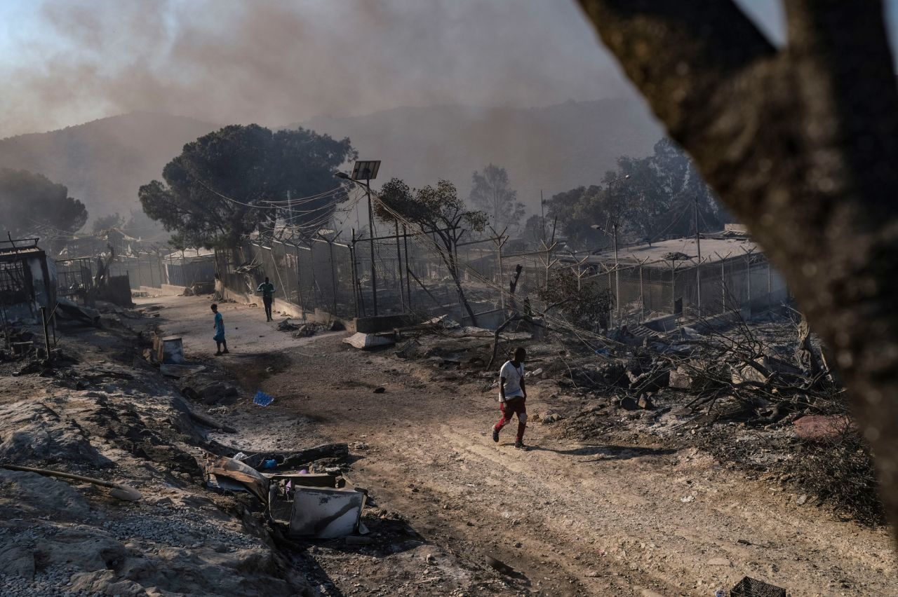 People walk through the remains of the burned-out Moria camp.