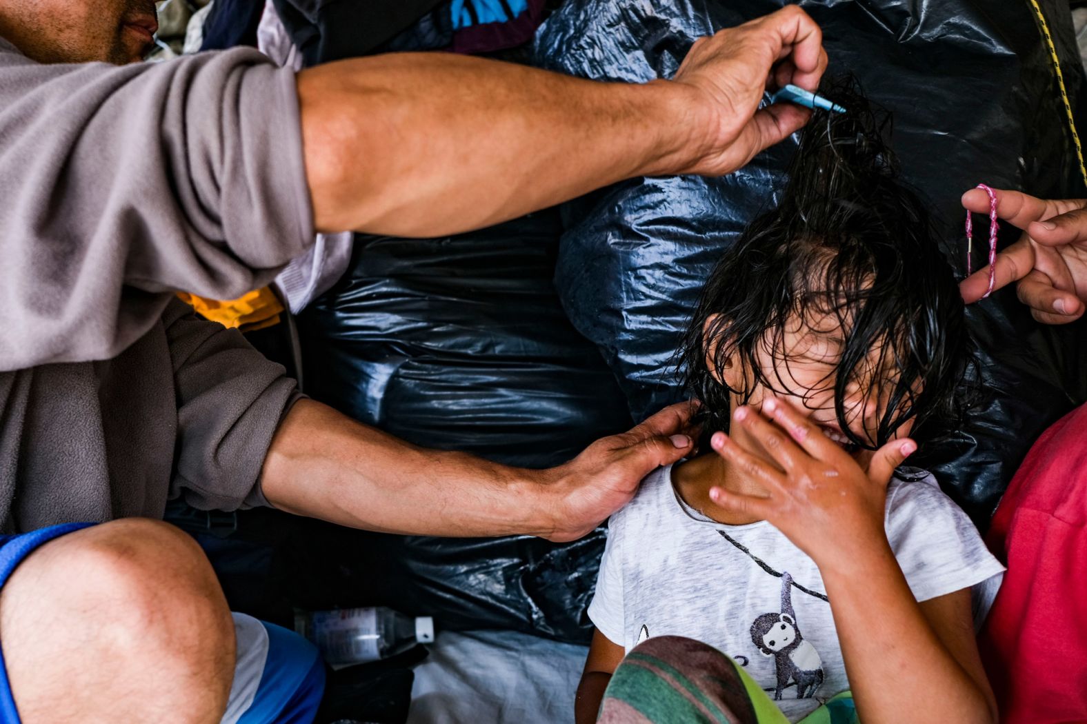 An Afghan migrant combs his daughter's hair on September 11.