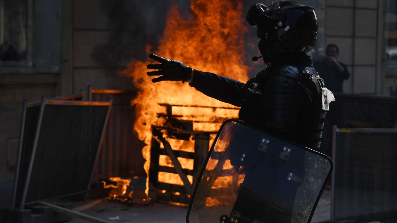 A riot police officer stands near a fire during a yellow vest protest in Paris on September 12.