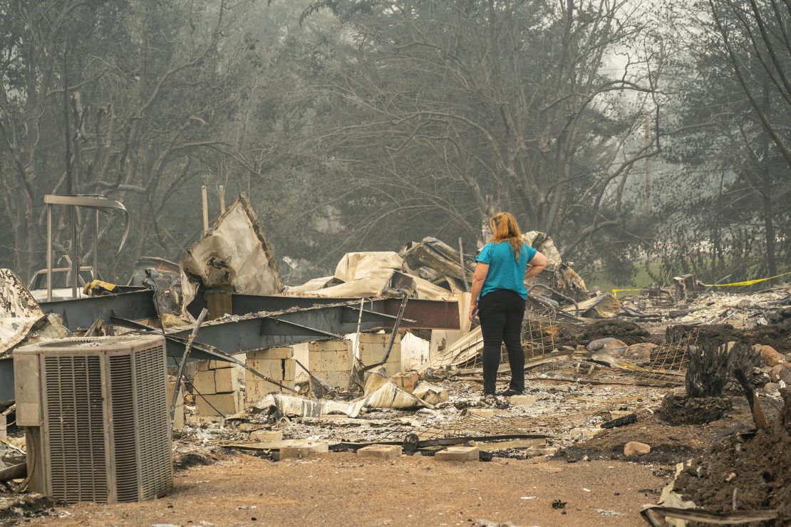A woman surveys the damage to a home owned by her son in a mobile home park on September 11, 2020 in Ashland, Oregon. 