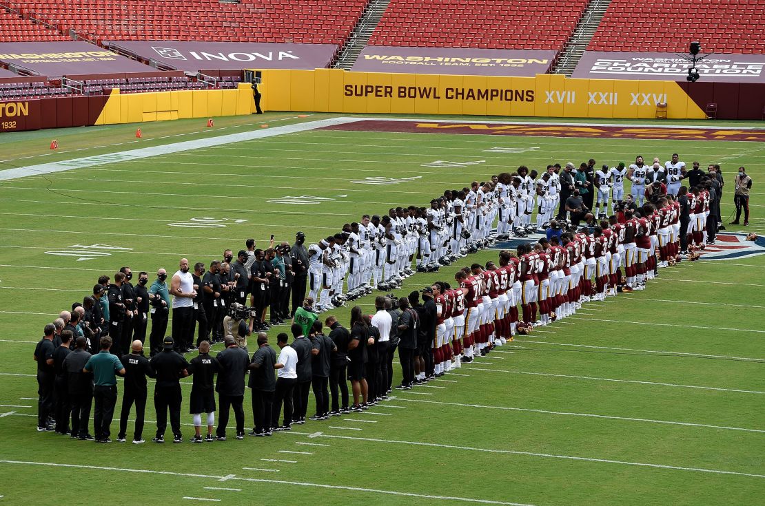 The Washington Football Team and the Philadelphia Eagles stand together on the field before the game at FedExField in Landover, Maryland, on Sunday, September 13. 