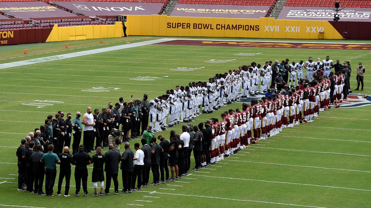 The Washington Football Team and the Philadelphia Eagles stand together on the field before the game at FedExField in Landover, Maryland, on Sunday, September 13.