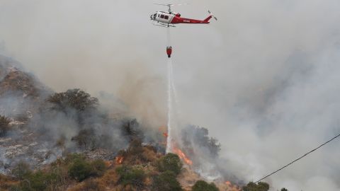 A helicopter drops water to help extinguish the Bobcat Fire.