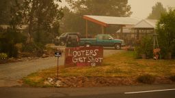 A sign warns that "Looters get shot" at a home near the Riverside Fire, Sunday, Sept. 13, 2020, near Molalla, Ore. (AP Photo/John Locher)