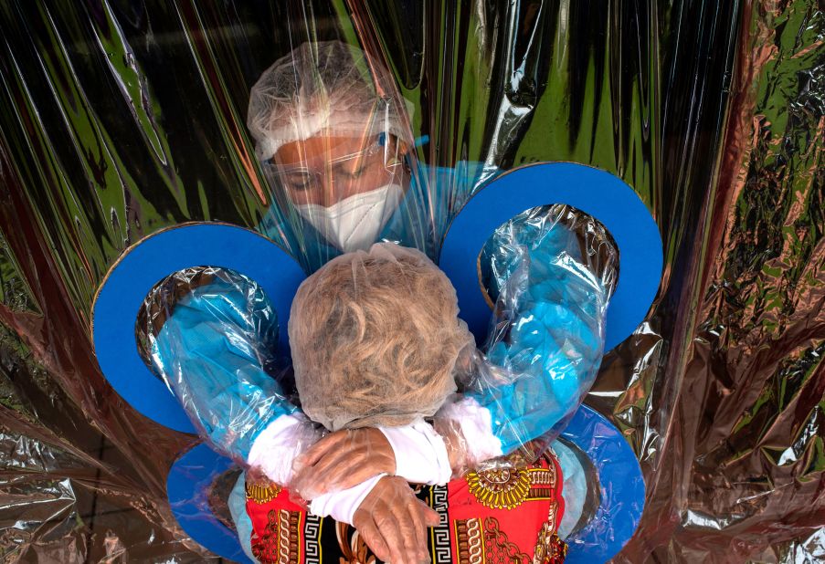 Maria Hernandez, top, embraces her aunt through a transparent curtain at a nursing home in San Salvador, El Salvador, on September 11.