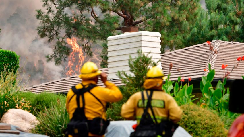 Firefighters keep an eye on the Bobcat Fire as it burns on a hillside behind homes in Arcadia, California on September 13, 2020 which prompted mandatory evacuations for residents living along the foothils of the San Gabriel Mountains.