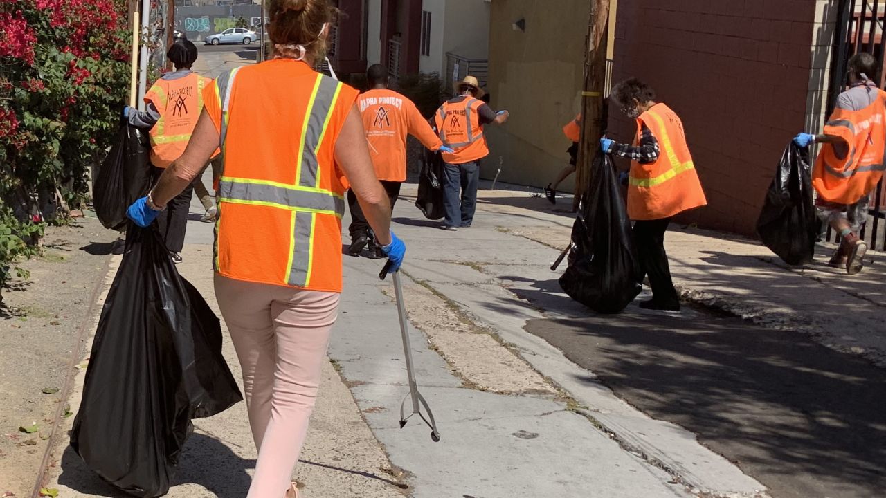 Clad in orange vests, homeless people working with Wheels of Change approach their assigned area to clean up. Wheels of Change pays 20 people each day to pick up litter around San Diego, in an effort to lift them out of homelessness.