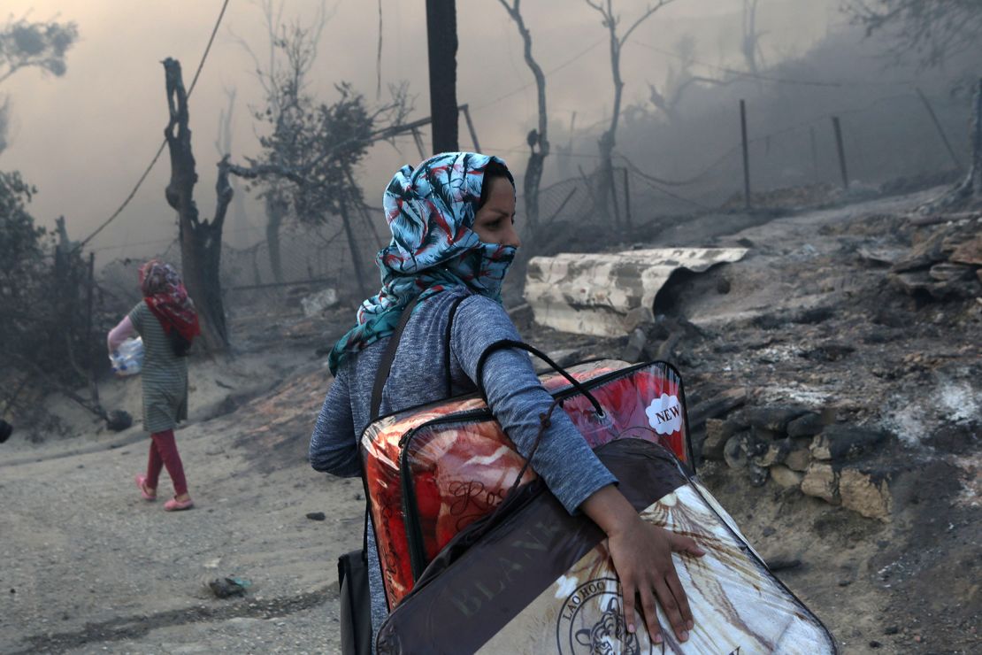 A migrant carries her belongings following the devastating blaze at the Moria camp on September 9.