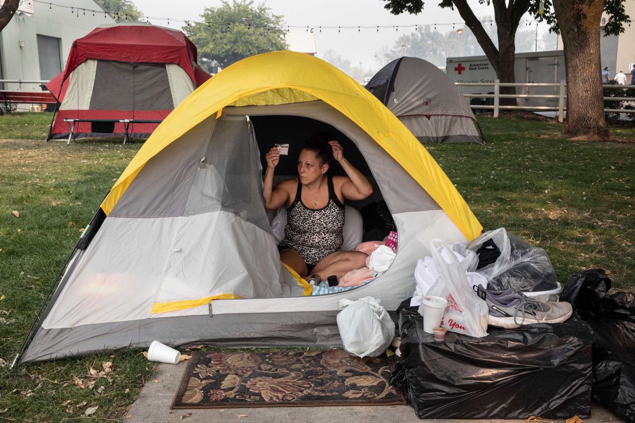 Stacey Kahny fixes her hair inside her tent at the evacuation center at the Jackson County Fairgrounds in Central Point, Oregon, on September 16, 2020. Kahny lived with her parents at a trailer park in Phoenix, Oregon, that was destroyed by fire.