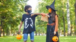 Two friends in Halloween costumes playing with each other in the park