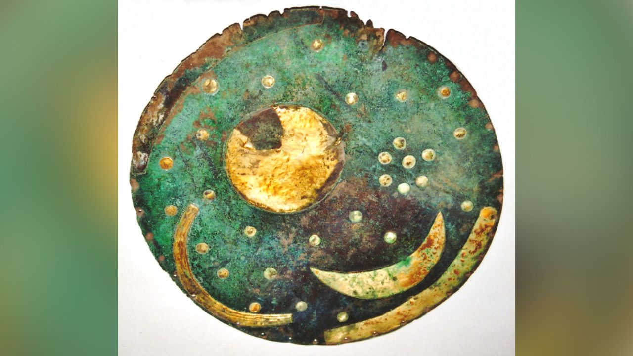 This image shows the Nebra sky disc in 2002. The disc includes a crescent moon as well as other cosmic features and depicts an abstract representation of a starry night.