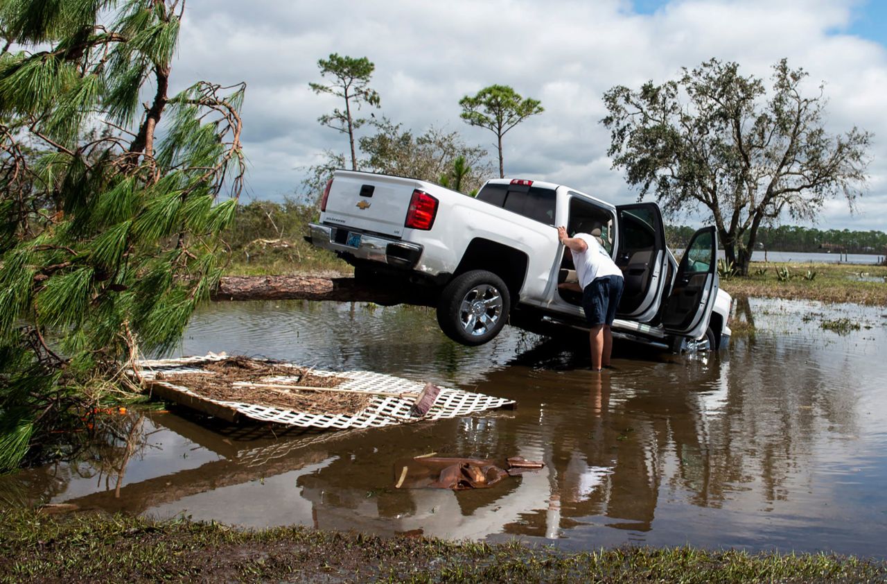 A man checks on his truck as it rests on a tree in Perdido Key, Florida, on Thursday, September 17.