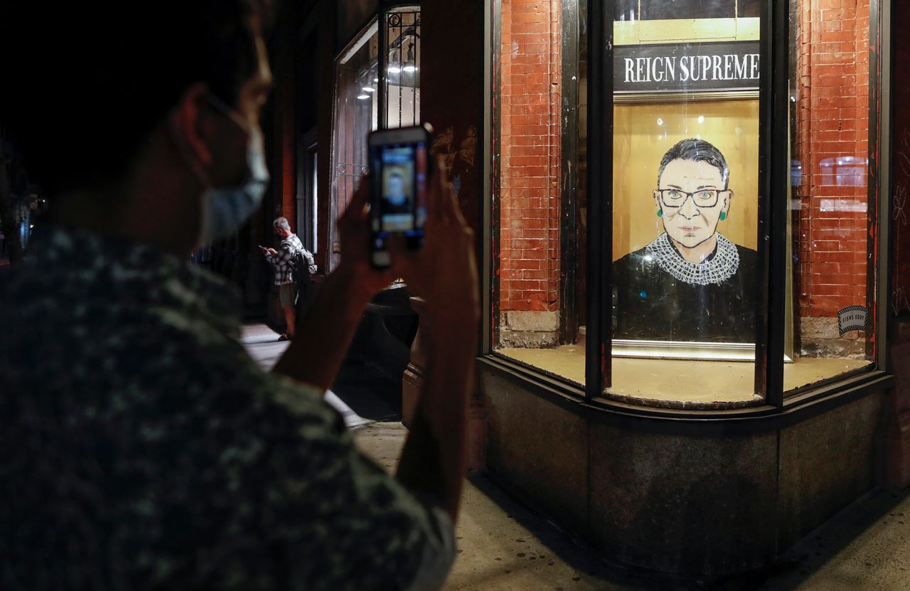 A person pauses to photograph a painting of Ginsburg outside a New York storefront on September 18. 