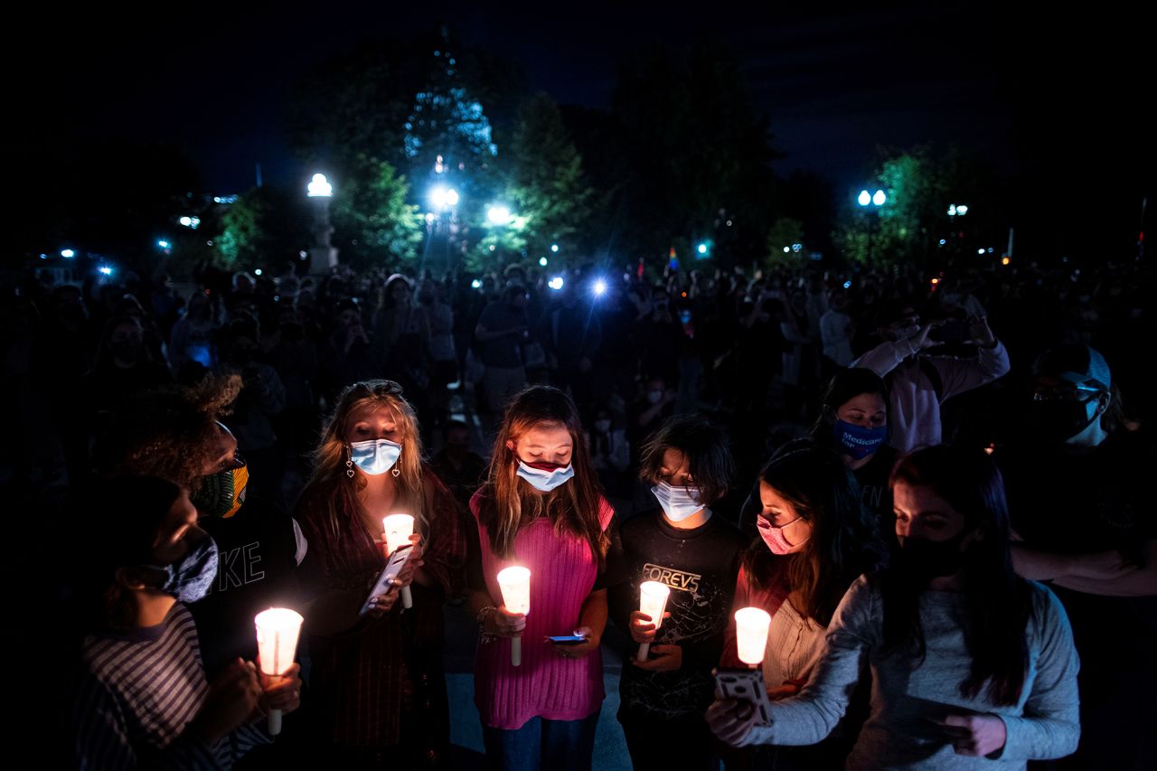 A group of women holds candles while gathering in front of the Supreme Court.