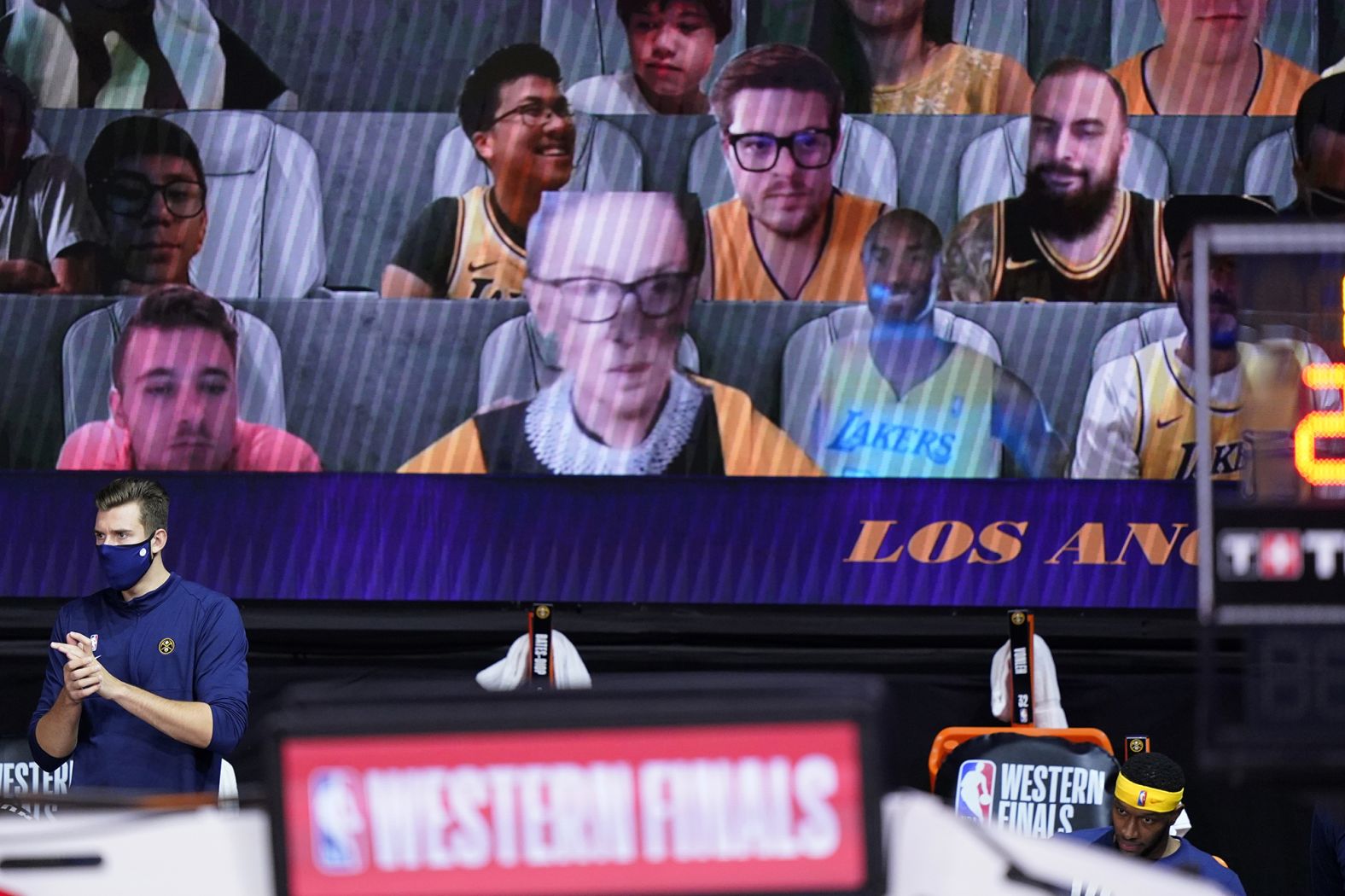 A video board showing virtual fans includes a cutout of Ginsburg, center left, and the late Kobe Bryant, center right, during the first half of an NBA playoff game on September 18.