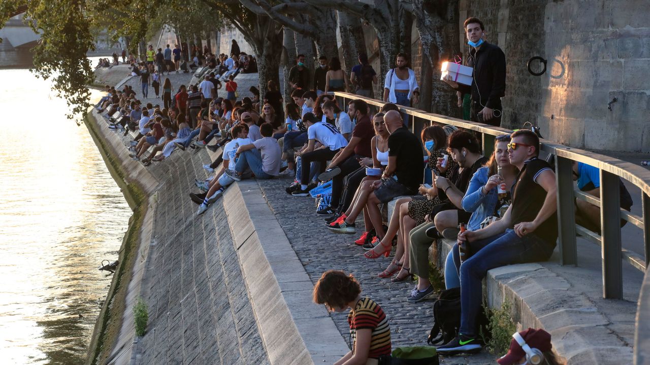 People gather along the Seine river bank during sunset in Paris, on Thursday, amid the resurgence of the coronavirus.