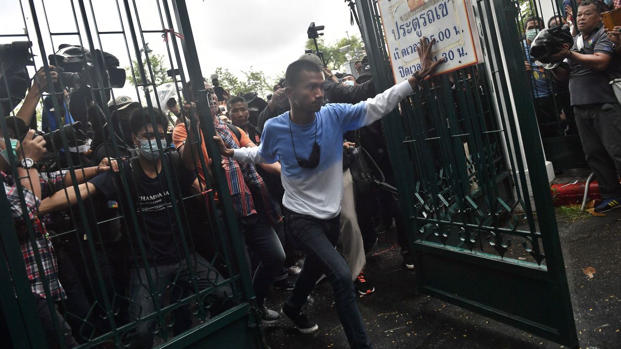 Anti-government protesters led by activist Panupong "Mike" Jadnok, center, break through a gate at Thammasat University as they arrive for a pro-democracy rally on September 19.