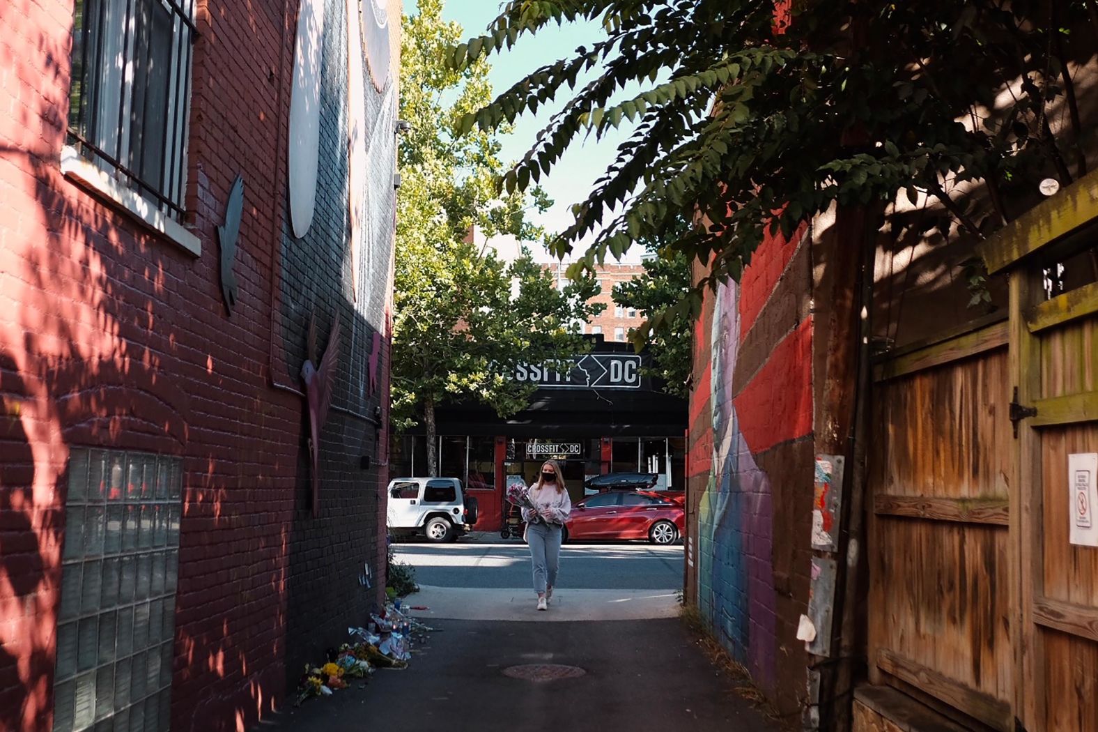 A woman brings flowers to the mural on U Street.