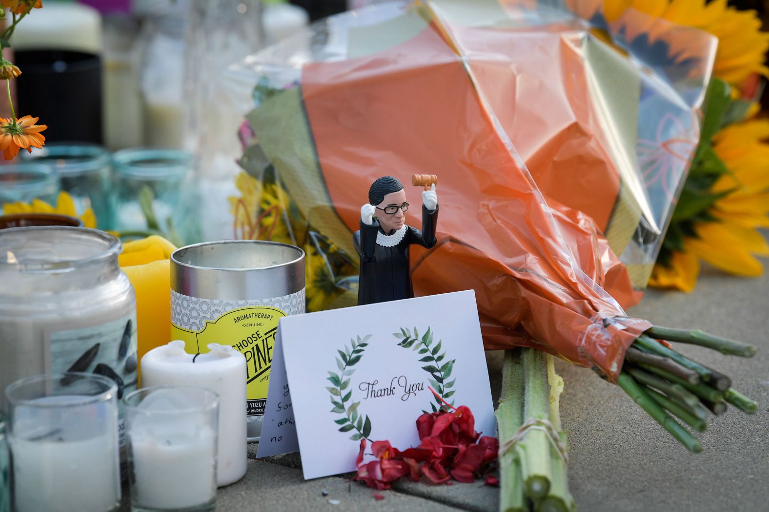 An action figure of Ginsburg is placed among cards, flowers and candles at her makeshift memorial outside of the Supreme Court.