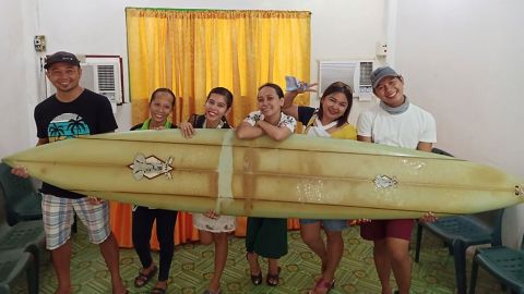 Filipino teacher Giovanne Branzuela (L) and his villagemates pose with the surfboard previously lost by big-wave surfer Doug Falter in Hawaii.