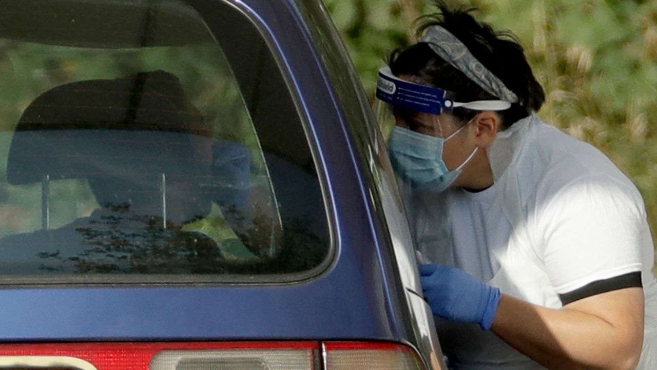 A person is tested for COVID-19 at a drive-through testing centre in a car park at Chessington World of Adventures, in Chessington, Greater London, Saturday, Sept. 19, 2020. England is preparing for more restrictions on gatherings and other activities in several areas of the country. There is growing speculation Britain may be sliding toward a lockdown in the coming weeks, partly because the testing regime is struggling to cope with higher demand. (AP Photo/Matt Dunham)