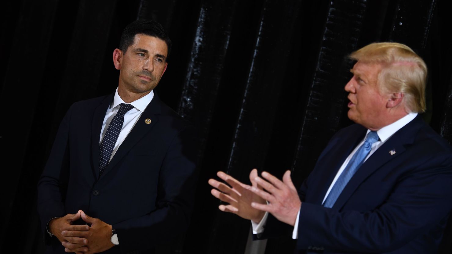 Acting Secretary of Homeland Security Chad Wolf (L) looks on as President Donald Trump delivers remarks on immigration and border security to members of the Border Patrol at the international airport in Yuma, Arizona, on August 18, 2020. 