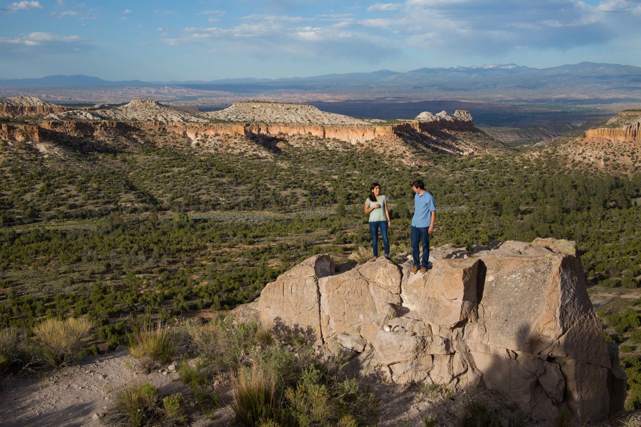 Two hikers stand in a mountain valley in Los Alamos County, New Mexico.