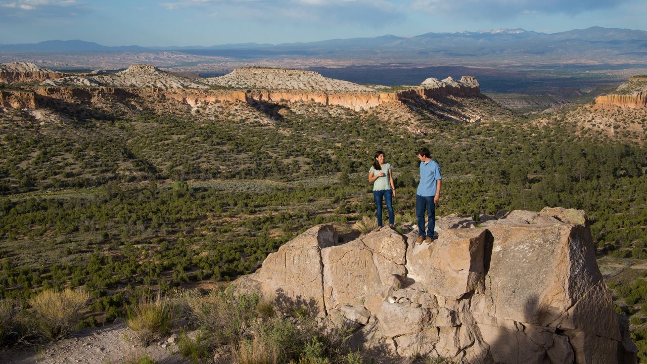 Two hikers stand in a mountain valley in Los Alamos County, New Mexico. 