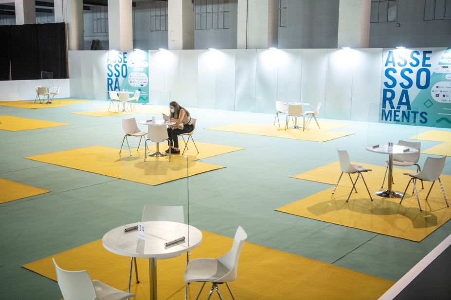 An adviser waits for people behind a plastic glass screen during a job fair in Barcelona, Spain, on September 21.