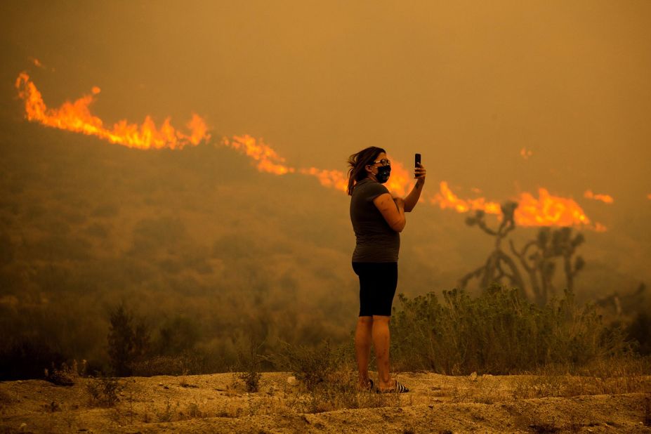 A woman takes photos as the Bobcat Fire burns in Juniper Hills, California, on September 18, 2020.