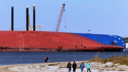 People walk the beach near the Golden Ray cargo ship on February 27, 2020 in Jekyll Island, Georgia. In about a month, a salvage company will begin cutting the vessel into eight segments which can be lifted out of the water and removed by a barge. The vehicle carrier, loaded with 4200 new cars, capsized in St. Simons Island Sound on September 8, 2019 as it was leaving the Port of Brunswick.  (Photo by Paul Hennessy/NurPhoto via Getty Images)