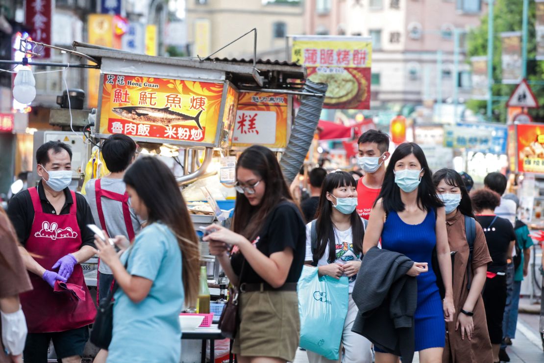 People wearing protective masks walk past food stalls at the Ningxia Night Market in Taipei, Taiwan, on July 30, 2020.