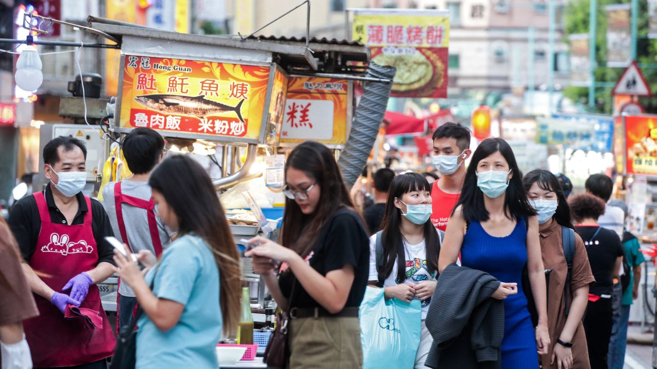 People wearing protective masks walk past food stalls at the Ningxia Night Market in Taipei, Taiwan, on July 30, 2020.